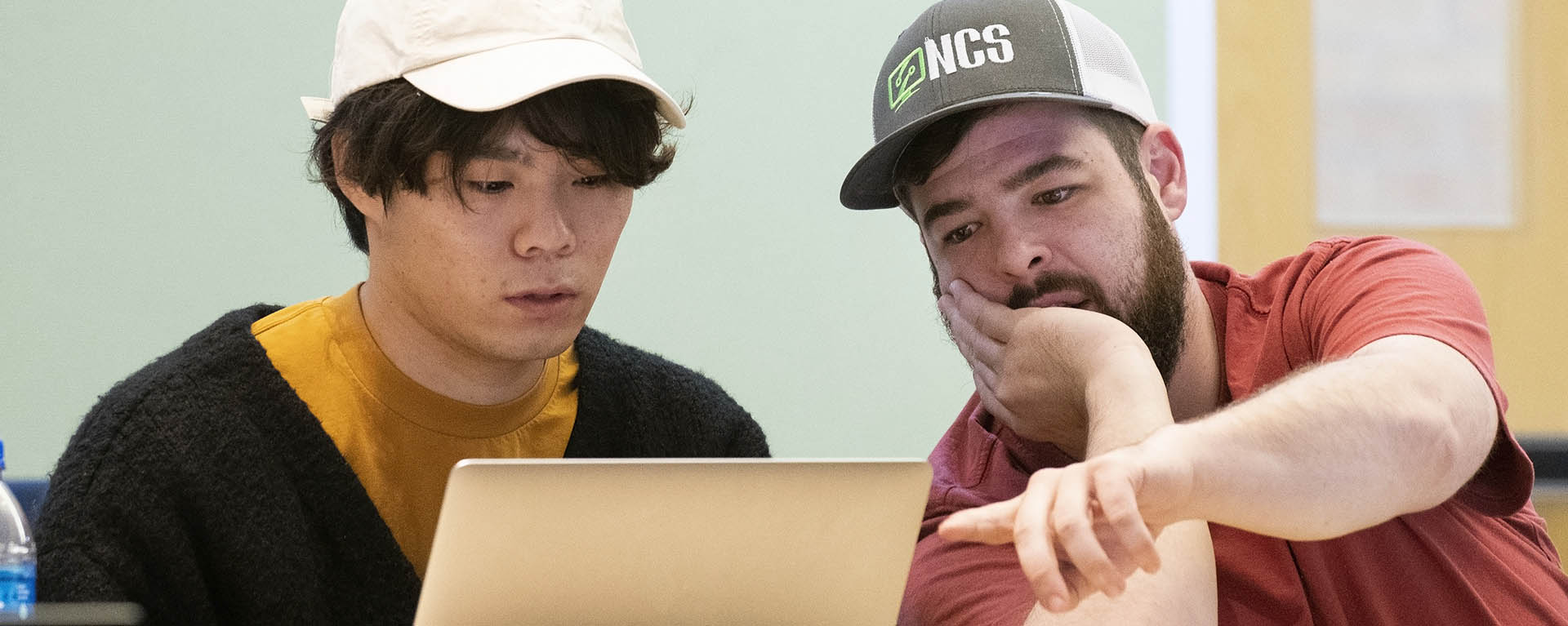 A student points to the screen while working on a project during class.