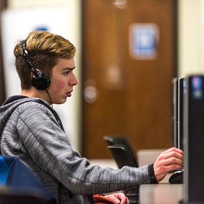 A student wearing headphones works on a pc