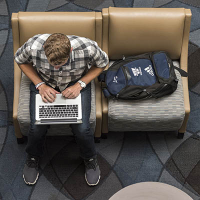 An overhead view of a student typing on a laptop in the welcome center.