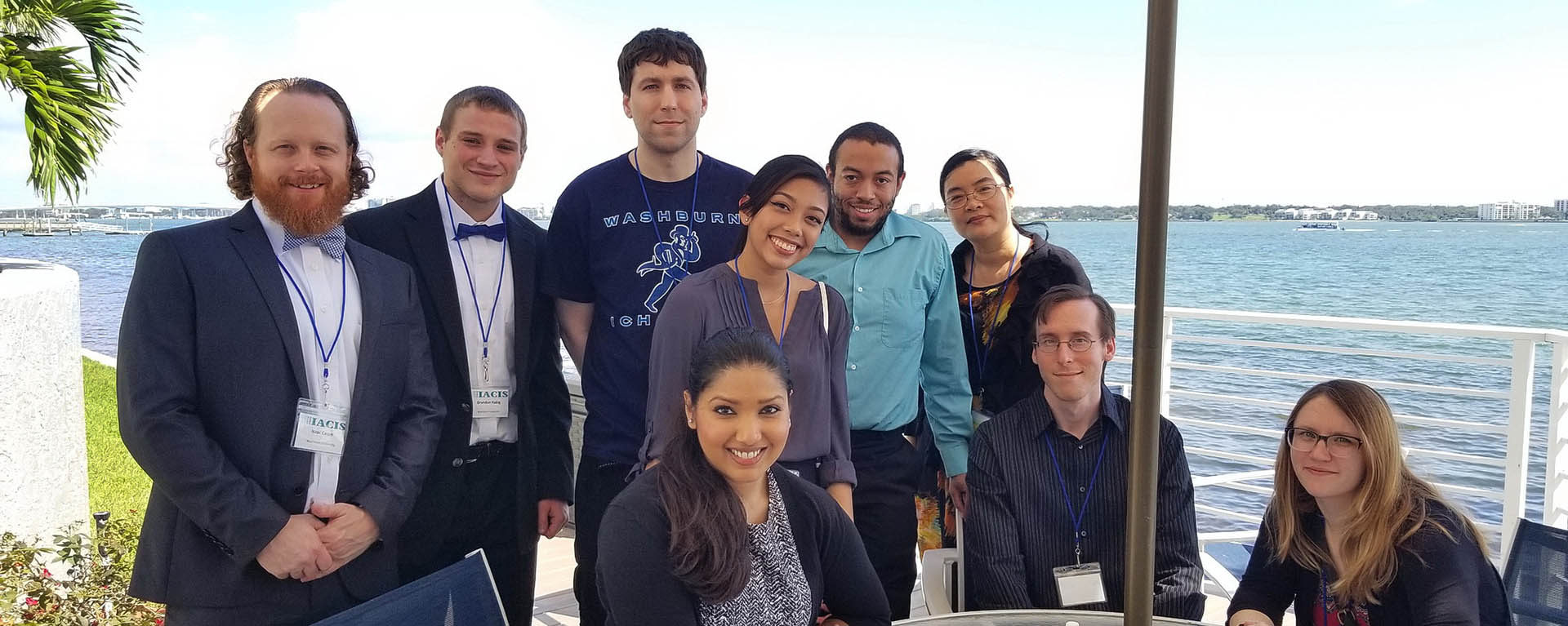 Students smile for a photo with an ocean view behind them while attending a conference.