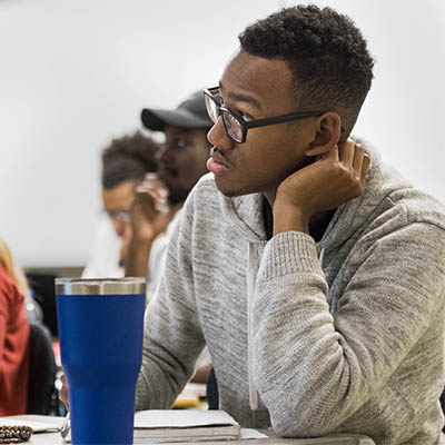 A student takes notes while listening to a lecture.