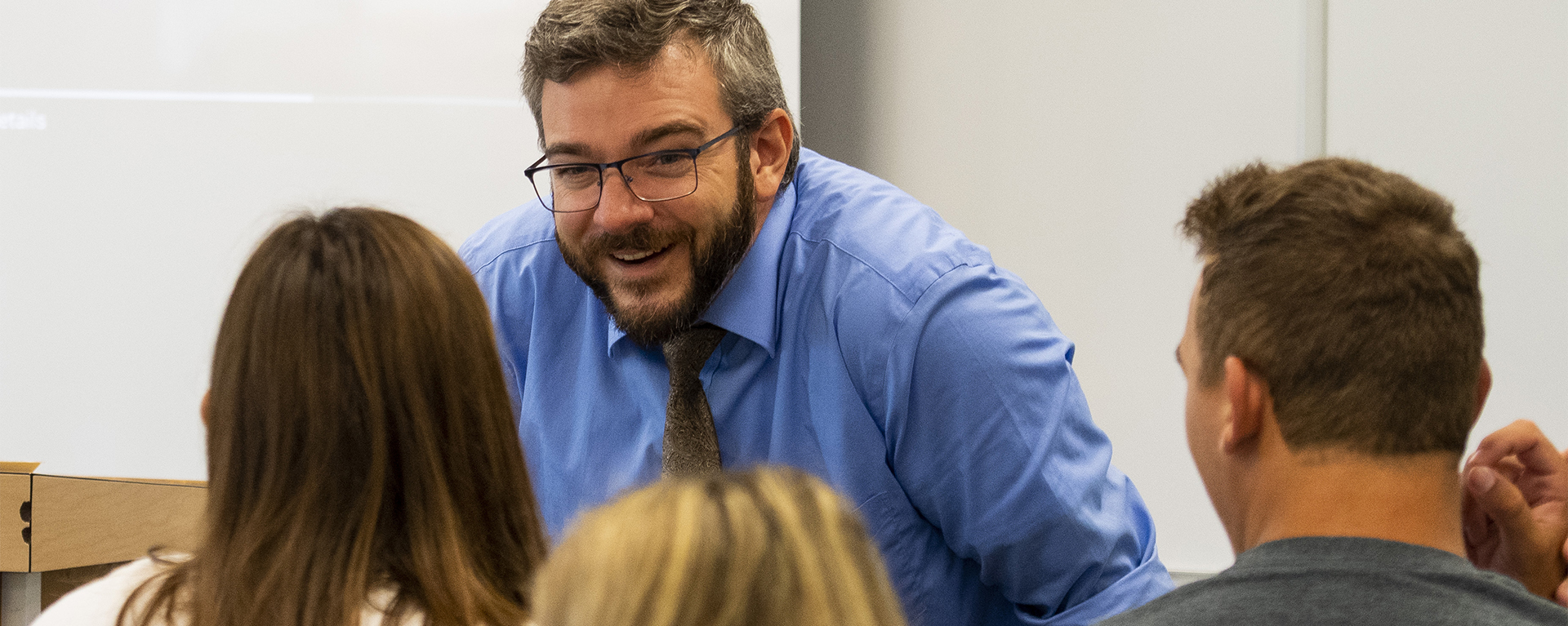 A professor smiles while talking with students.