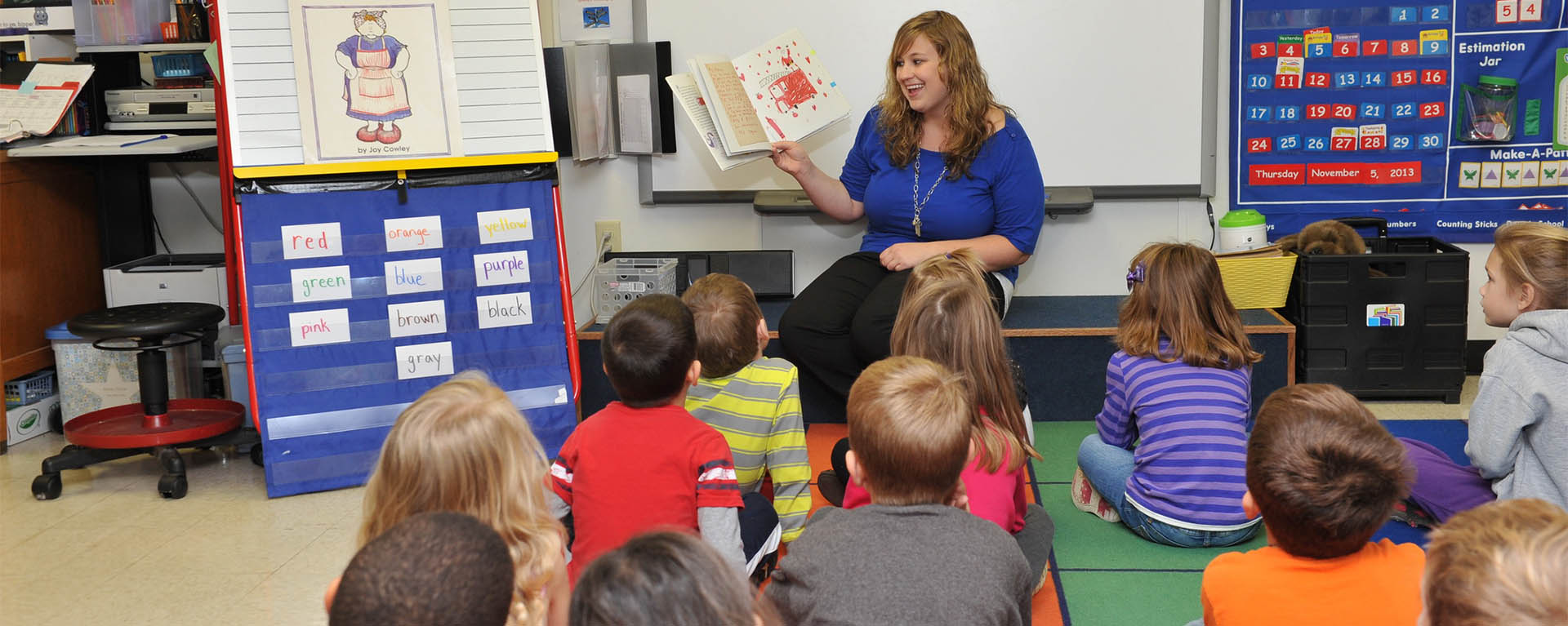 An education student reads to a group of kids in a classroom