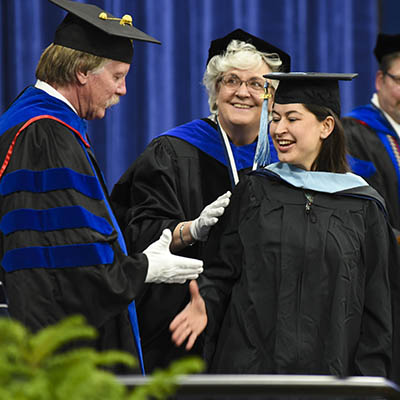 A student shakes hands on stage during graduation.