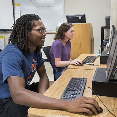 A student smiles while working on the computer.