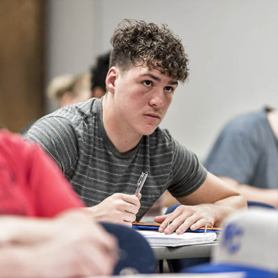 A student listens intently while taking notes in history class.