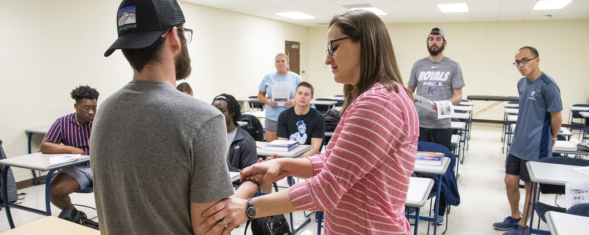 A professor demonstrates a reflex test in front of a class of kinesiology students.