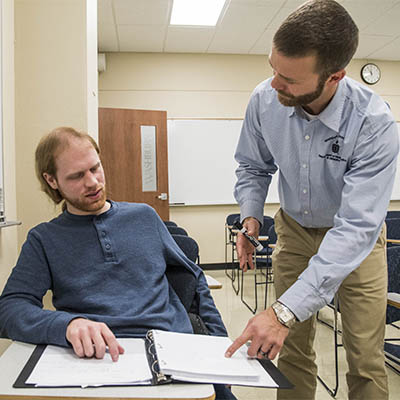 A math professor explains a problem to a student in class