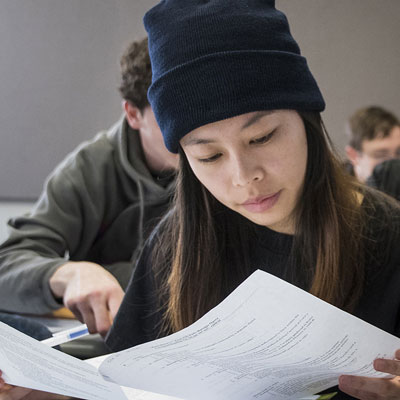 A student smiles while studying a paper