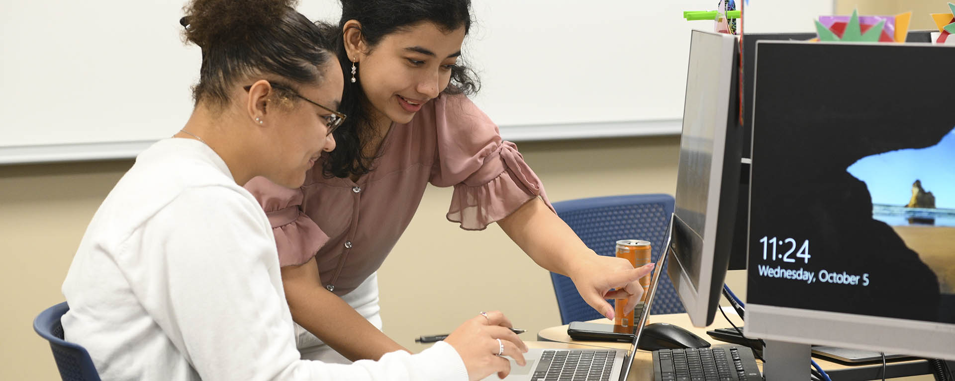 Two students work together on a math problem in a computer lab.