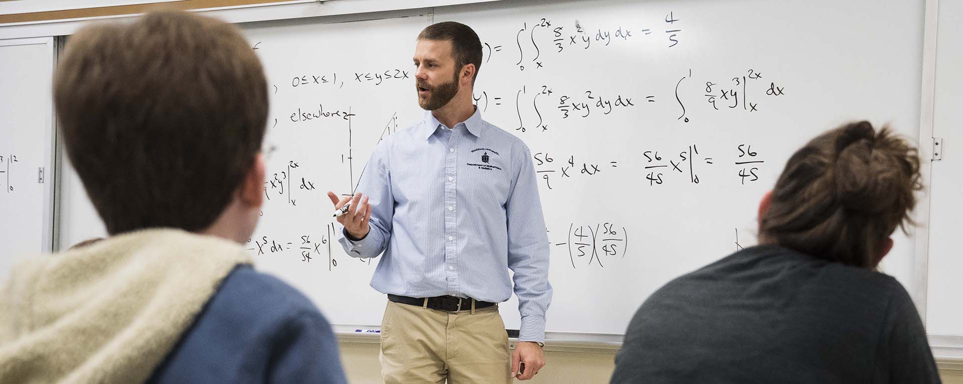 Dr. Shaw teaching a math class with equations written on the board.