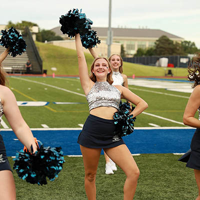 The Dancing Blues cheer on sidelines of football field