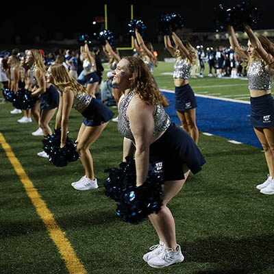 Dancing Blues cheer on sidelines at night time event