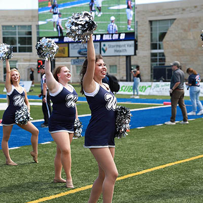 A group of Dancing Blues cheers on football field 