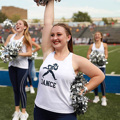 A Dancing Blue smiles and cheers with other Blues in the background