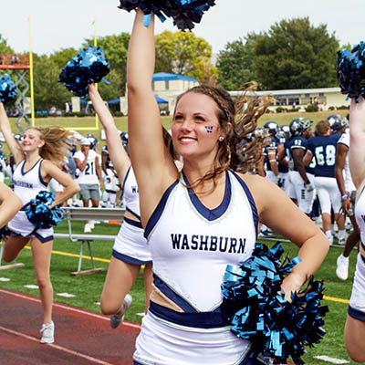 A dancing blue smiles and cheers while on the sidelines of a football game.