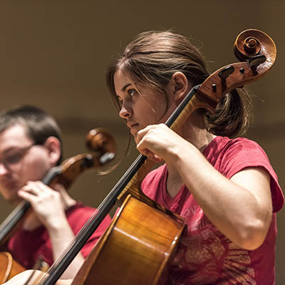 A student focuses on her music while playing the cello.