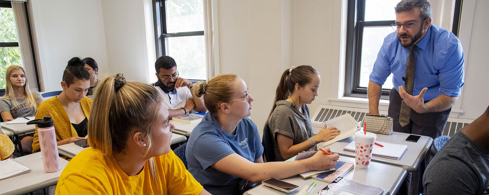 A religious studies professor talks with a group of students during class.