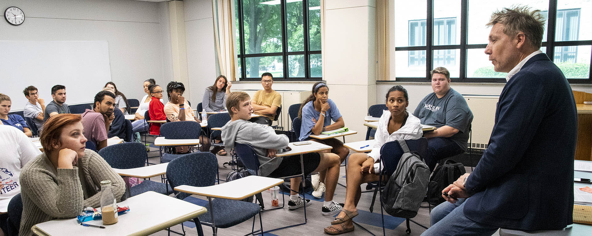 A philosophy professor talks with a group of students during a group discussion.