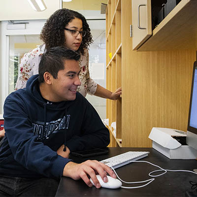 A student smiles while using a computer in a classroom for an experiment.