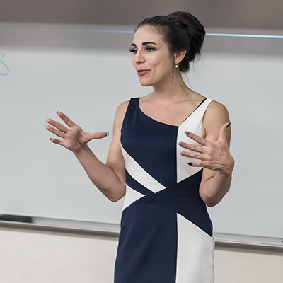 Psychology professor gestures while teaching in front of a whiteboard