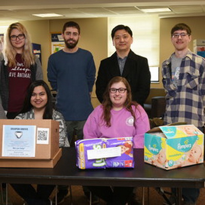 Students and a professor pose during a diaper drive for their sociology class.
