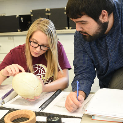 Two students examine a skull during class