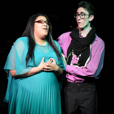 Two students sing while on stage for a production.