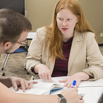 A Washburn student employee tutors another student in the library.