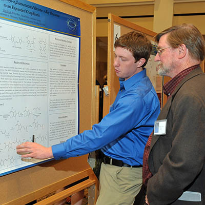 Apeiron student discussing poster info with professor