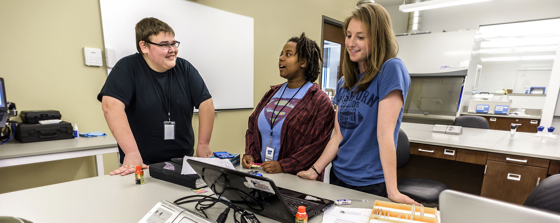 Forensics students talk while standing in a lab in the KBI lab.