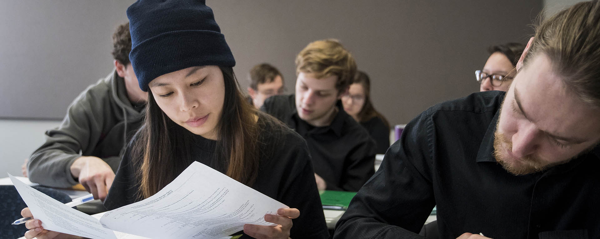 A student looks through sheets of paper while in class.