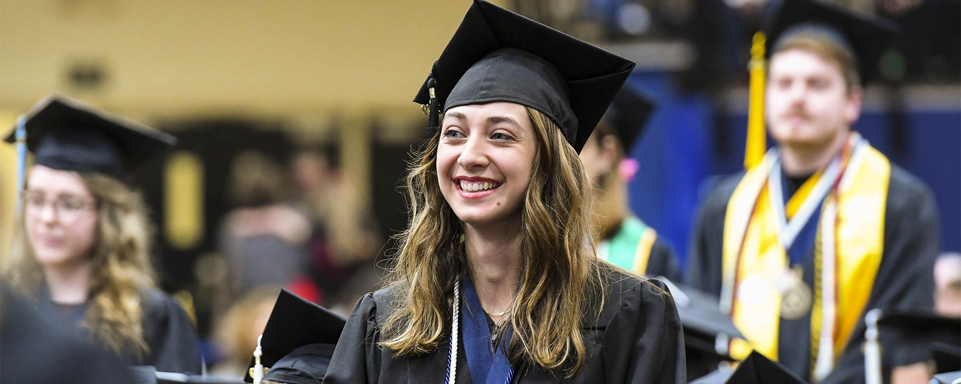 A student smiles while being recognized at a graduation ceremony.
