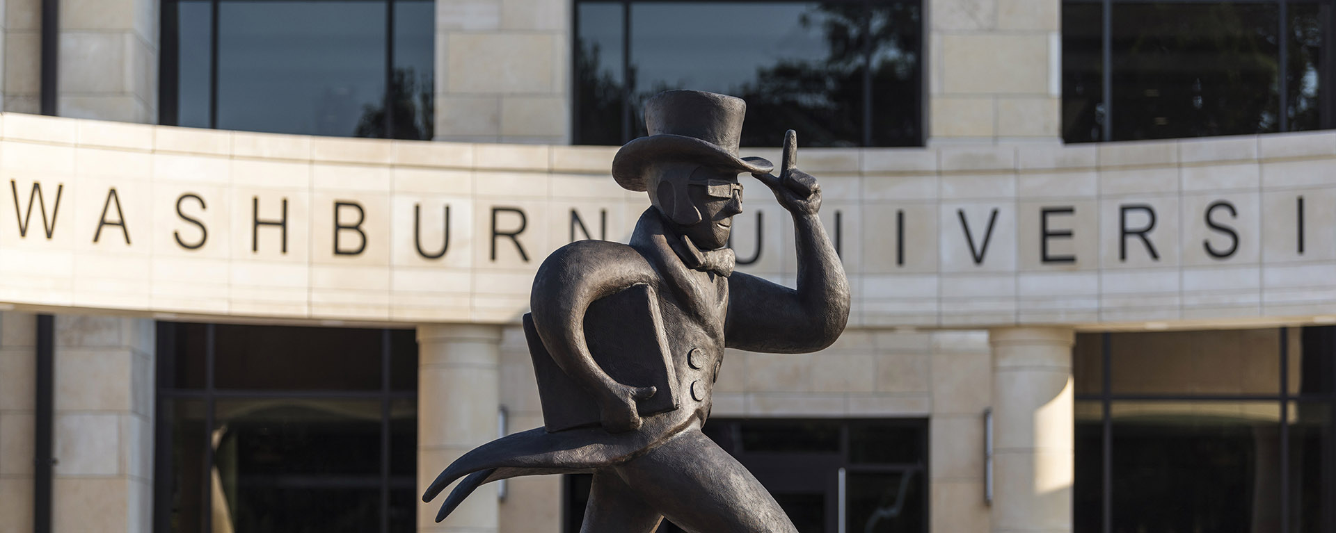 Image of Ichabod statue in front of Morgan Hall, with Washburn University sign behind it