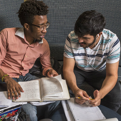 Two students talk while studying.