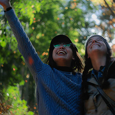 Two students among trees looking at the sky