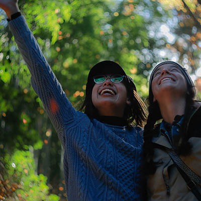 Two students among trees looking at the sky 