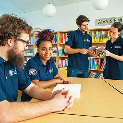 group of people smiling and talking around a table wearing dark blue vista americorp shirts
