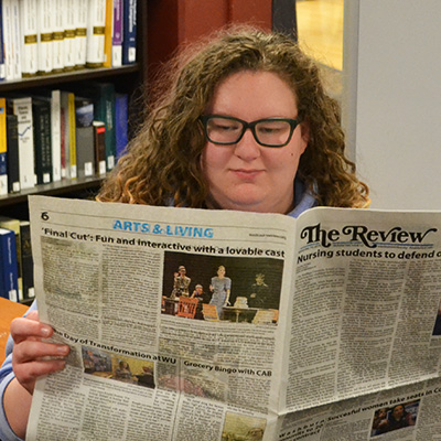 female student reading a news paper