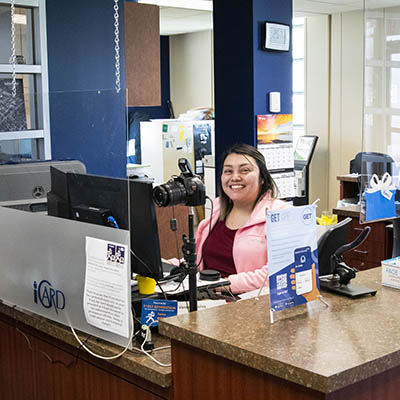 A worker smiles behind iCard service desk.