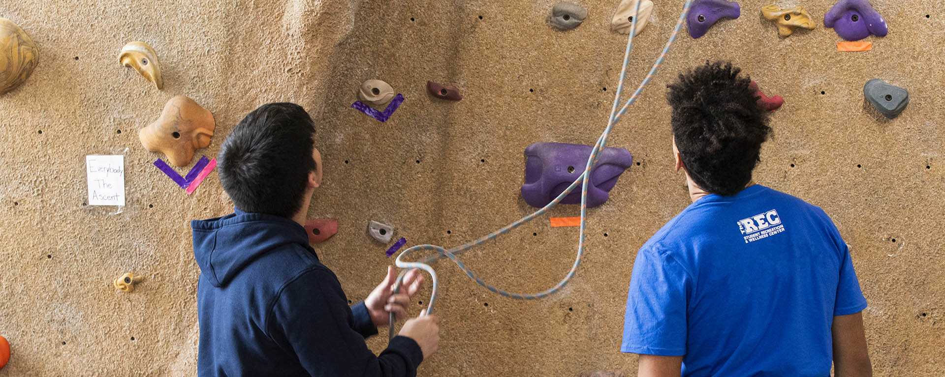 Students prepare to climb the rock wall.