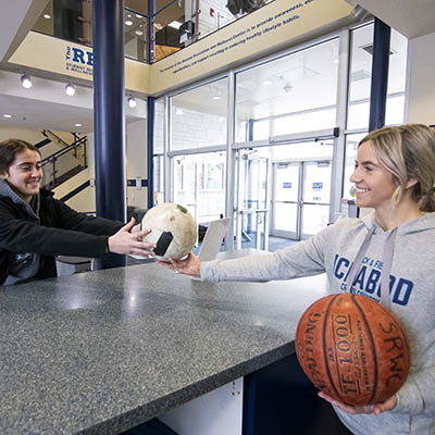 A SRWC employee hands out a basketball to a student.