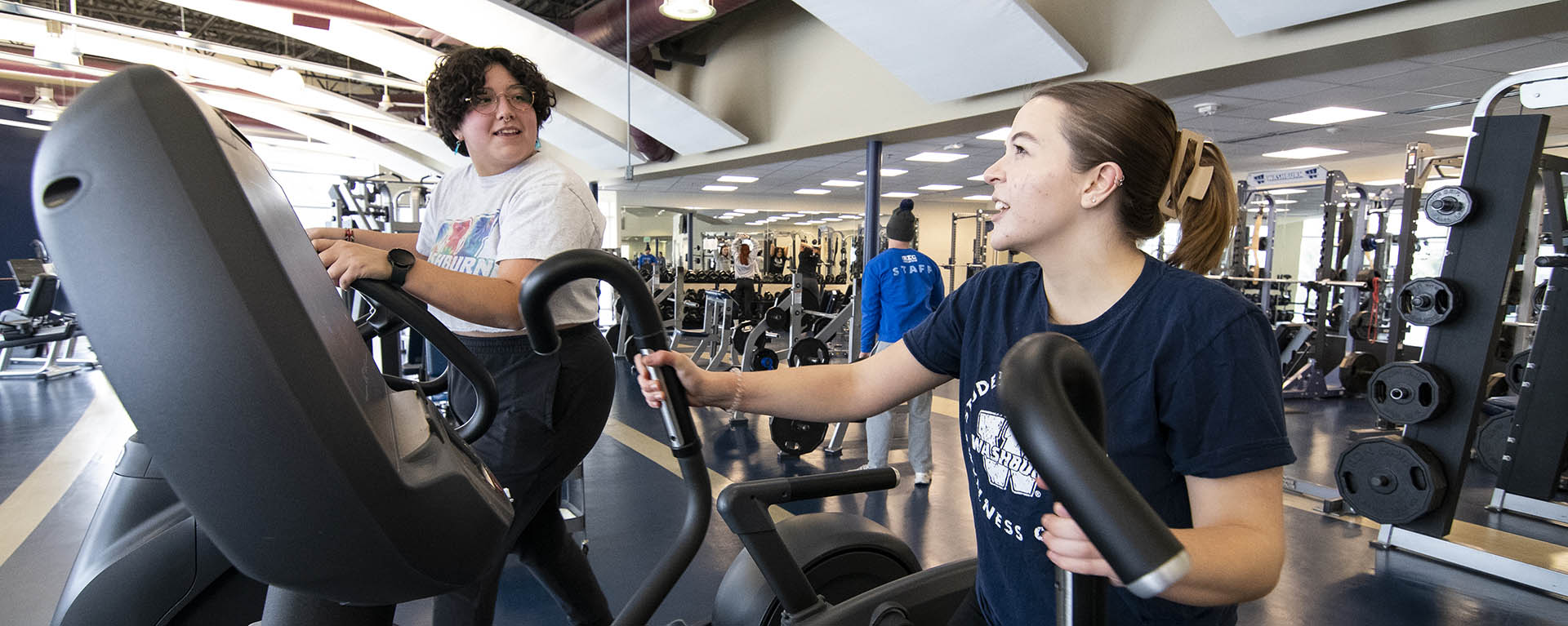 Students talking while on elliptical machines.