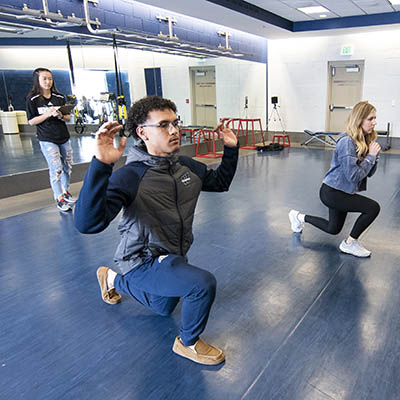 A trainer watches as students perform a fitness assessment exercise.