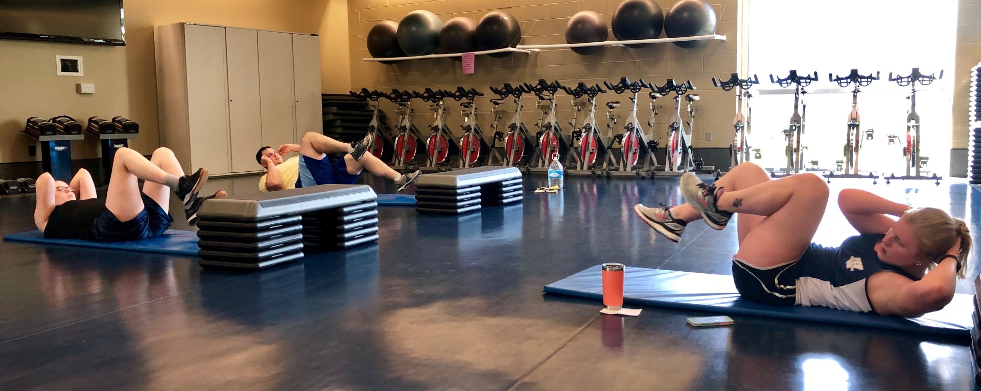 3 people doing sit ups in a gym