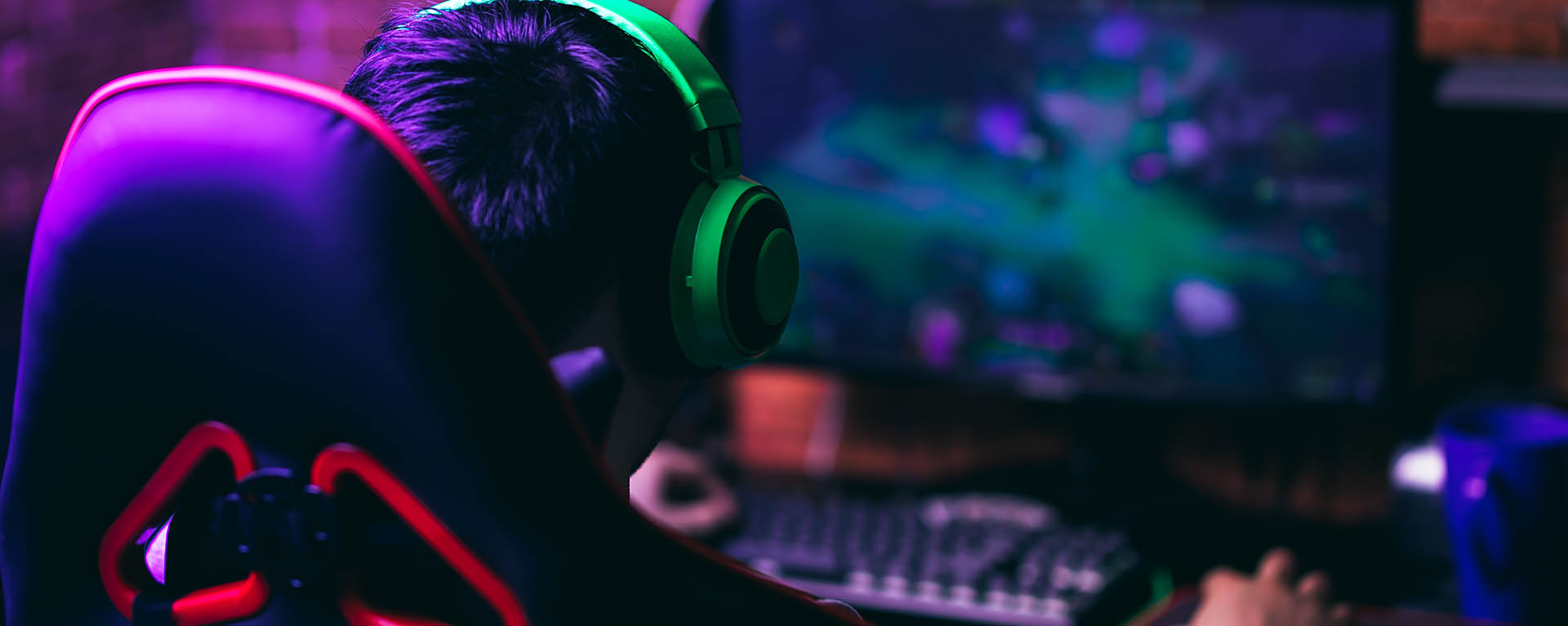 student in gaming chair with headphones on facing a monitor