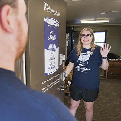 A student waves and welcomes a person into the pantry.