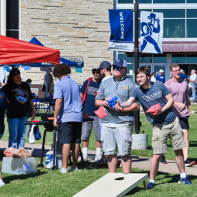 A student and their dad play corn hole during a tailgate on the Memorial Union lawn.
