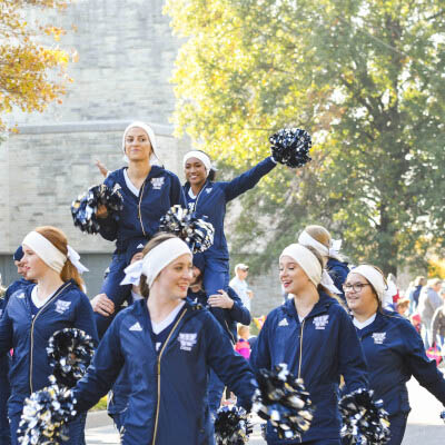 Cheerleaders marching in parade and waving pom-poms