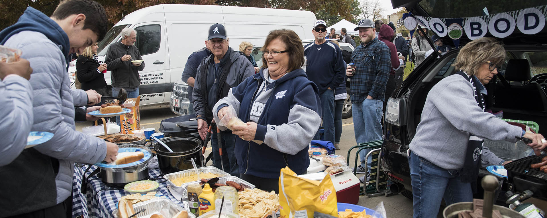 A mom prepares food at the football tailgate.